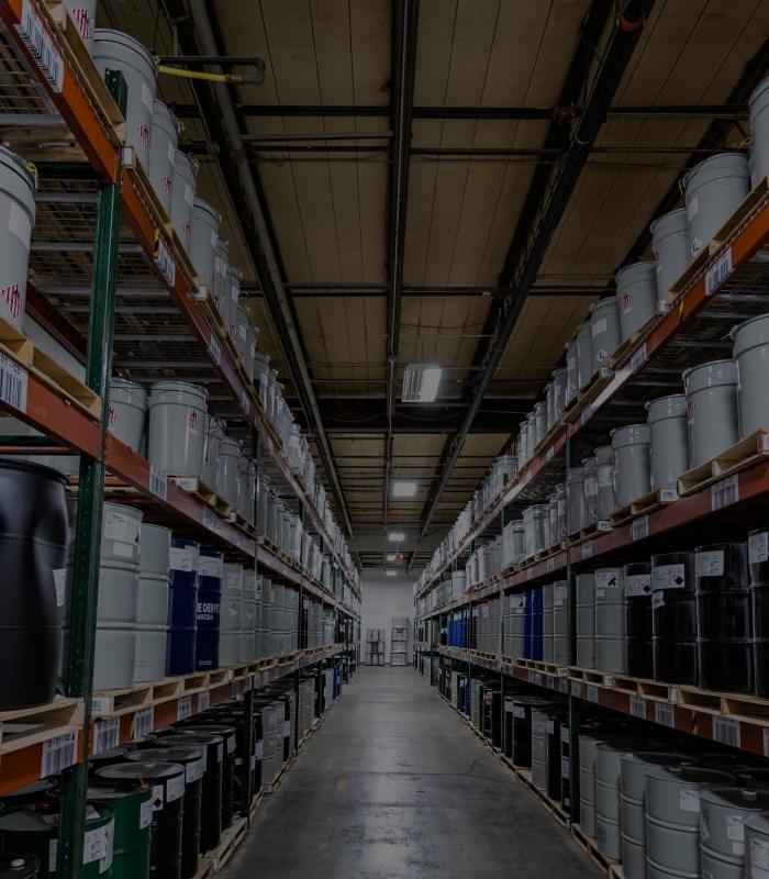 An aisle with shelves of barrels stacked on pallets on either side